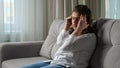 Disabled woman suffers from headache sitting on sofa at home Royalty Free Stock Photo