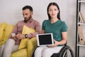 Disabled woman showing digital tablet with blank screen while sitting near boyfriend using smartphone Royalty Free Stock Photo