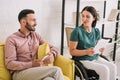 Disabled woman using digital tablet near boyfriend sitting on sofa with smartphone Royalty Free Stock Photo