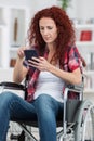 Disabled woman wheel chair and typing message with smartphone