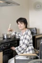 Disabled woman in wheelchair cooking dinner