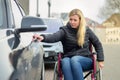 Disabled woman in a wheelchair opening a car