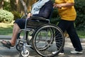 Disabled woman in a wheelchair relaxing in a park with a care assistant