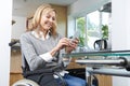 Disabled Woman In Wheelchair Texting On Mobile Phone At Home Royalty Free Stock Photo