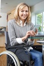 Disabled Woman In Wheelchair Texting On Mobile Phone At Home Royalty Free Stock Photo