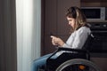 Disabled woman in wheelchair tries to use smartphone at home Royalty Free Stock Photo
