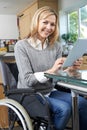 Disabled Woman In Wheelchair Using Digital Tablet At Home Royalty Free Stock Photo