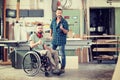 Worker in wheelchair in a carpenter`s workshop with his colleagu Royalty Free Stock Photo