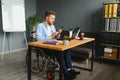 Disabled Young Businessman On Wheelchair Giving Presentation To His Colleague In Office Royalty Free Stock Photo