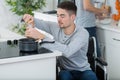 Disabled young man in wheelchair cooking in kitchen