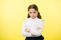 Disagreement and stubbornness. Girl school uniform serious face offended yellow background. Kid unhappy looks strictly