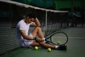 Disappointed asian male tennis player sitting on the court, upset about competition loss, failure emotions Royalty Free Stock Photo