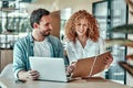 Disappointed businesswoman looking in notebook with coworker in cafe Royalty Free Stock Photo