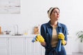 Disappointed housewife in rubber gloves holding