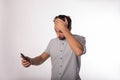 Disappointed man holds his head in his hand and reading shocked news in message on mobile phone