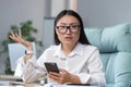 Disappointed and sad asian business woman reading bad news from phone, employee working in office Royalty Free Stock Photo