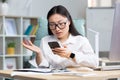Disappointed and sad asian business woman reading bad news from phone, employee working in office Royalty Free Stock Photo