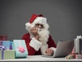 Disappointed Santa Claus connecting with his laptop Royalty Free Stock Photo