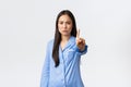 Disappointed serious and angry asian woman in blue pajamas shaking finger and frowning displeased, forbid something