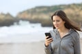 Disappointed teen reading phone message on the beach Royalty Free Stock Photo