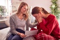 Disappointed Teenage Daughter Wearing Pyjamas Looking At School Exam Report With Mother In Bedroom Royalty Free Stock Photo