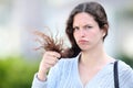 Disappointed woman holding hair looking at you