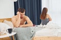 Disappointed woman sitting on the bed with back to the man that feels bad Royalty Free Stock Photo