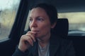 Disappointed and worried businesswoman looking out the window of taxi vehicle on cold rainy day