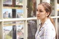 Disappointed Young Woman Looking In Window Of Estate Agents