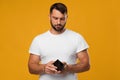 Disappointing sad middle aged european male look at empty wallet, isolated on yellow background Royalty Free Stock Photo