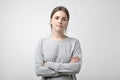 Frustrated young woman with crossed hands stands on white.