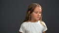 Disappointment little girl with long blond hair, looking thoughtful down wearing white t-shirt and black pants isolated
