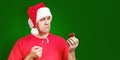 Man in Santa hat with candy cane in the hand holds bad small Christmas gift Royalty Free Stock Photo