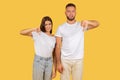 Disapproving young couple in white t-shirts giving thumbs down gestures with displeased expressions Royalty Free Stock Photo