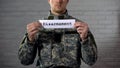 Disarmament word written on sign in hands of male soldier, end of war, peace