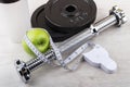 Disassembled dumbbell, green apple and measures tape