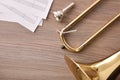 Disassembled golden trombone and scores on wooden table detail