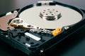 A disassembled open hard disk drive HDD of a computer or laptop close-up. Device lies on a dark matte surface. Tinted
