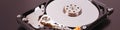 A disassembled open hard disk drive HDD of computer or laptop lies on brown matte surface. IT close-up. Banner about computer