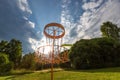 Disc golf basket and flying disc in summer park Royalty Free Stock Photo