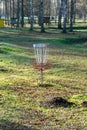 a disc golf hole on green grass with birch grove in background, disc golf basket in a park Royalty Free Stock Photo