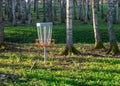 a disc golf hole on green grass with birch grove in background, disc golf basket in a park Royalty Free Stock Photo