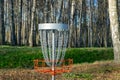 a disc golf hole on green grass with birch grove in background, disc golf basket in a park Royalty Free Stock Photo