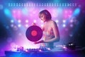 Disc jockey mixing music on turntables on stage with lights and stroboscopes