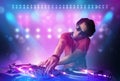 Disc jockey mixing music on turntables on stage with lights and