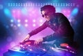 Disc jockey mixing music on turntables on stage with lights and