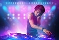 Disc jockey mixing music on turntables on stage with lights and