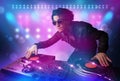 Disc jockey mixing music on turntables on stage with lights and