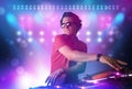 Disc jockey mixing music on turntables on stage with lights and