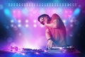 Disc jockey mixing music on turntables on stage with lights and